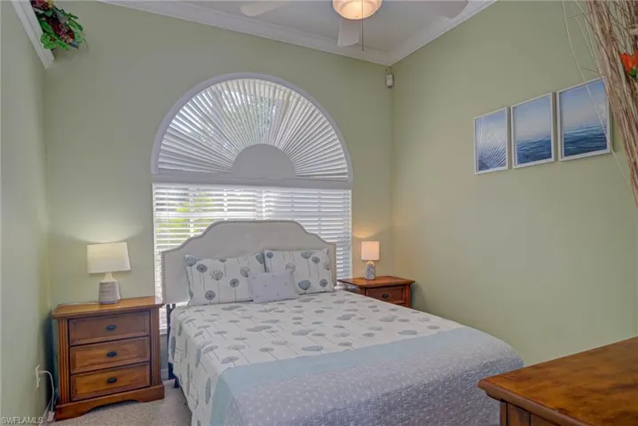 Carpeted bedroom featuring a ceiling fan and crown molding