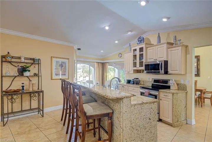 Kitchen featuring a kitchen breakfast bar, light tile patterned floors, ornamental molding, and appliances with stainless steel finishes