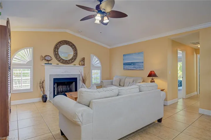 Living area featuring light tile patterned flooring, crown molding, a ceiling fan, and plenty of natural light