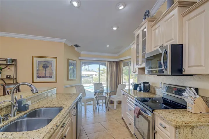 Kitchen with light stone countertops, a sink, crown molding, and appliances with stainless steel finishes