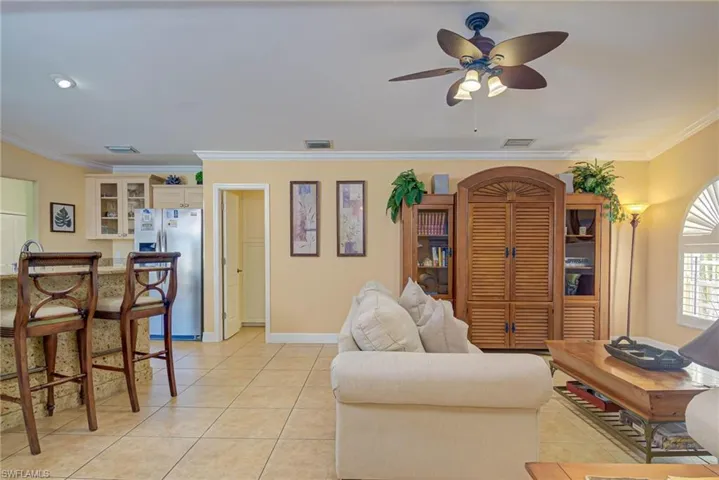 Living room featuring light tile patterned flooring, ornamental molding, and visible vents
