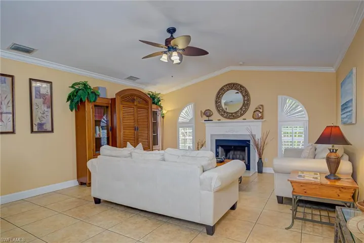 Living room featuring a ceiling fan, crown molding, and visible vents