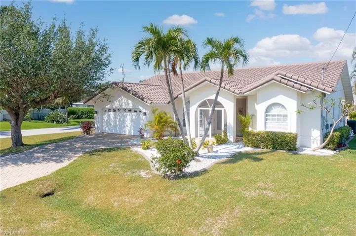 Mediterranean / spanish-style house featuring a tiled roof, decorative driveway, an attached garage, a front lawn, and stucco siding