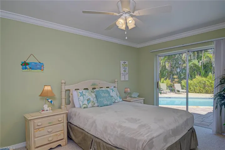 Carpeted bedroom featuring ornamental molding, baseboards, access to exterior, and ceiling fan