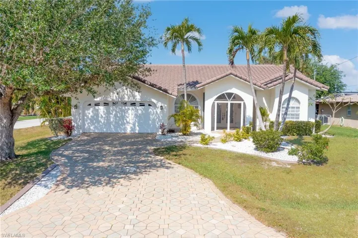 Mediterranean / spanish-style house featuring a tiled roof, decorative driveway, an attached garage, stucco siding, and french doors