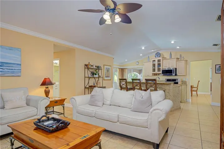 Living area featuring visible vents, lofted ceiling, and ornamental molding