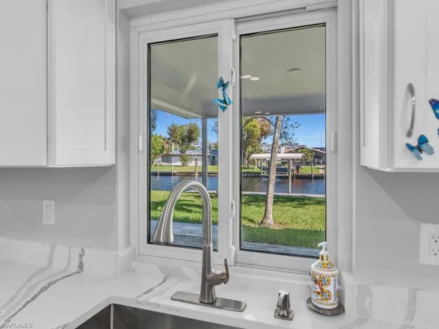 Details featuring sink, a water view, white cabinetry, and light stone counters