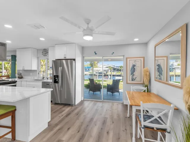 Kitchen with appliances with stainless steel finishes, light wood-type flooring, white cabinetry, and a healthy amount of sunlight