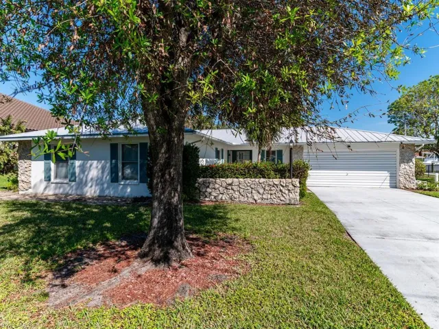 Single story home with a garage and a front lawn