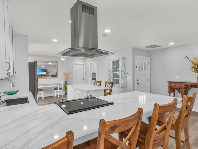Kitchen featuring island range hood, light hardwood / wood-style flooring, white cabinets, and sink
