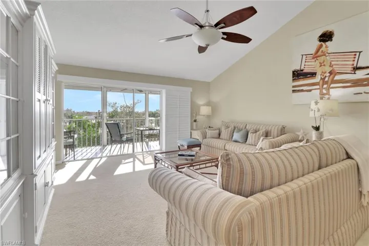 Living room with vaulted ceiling, light colored carpet, and a ceiling fan