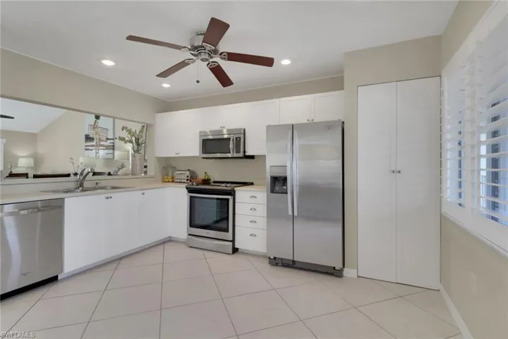 Kitchen with stainless steel appliances, white cabinetry, light countertops, light tile patterned floors, and a ceiling fan