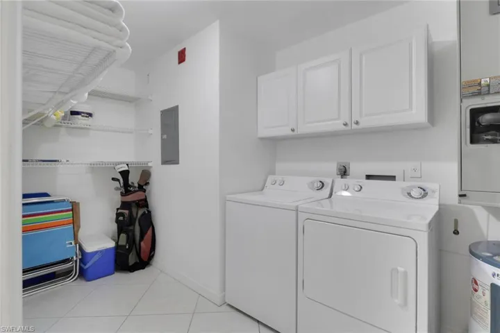 Laundry room featuring light tile patterned flooring, cabinet space, electric water heater, separate washer and dryer, and electric panel