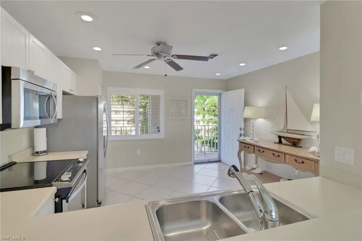Kitchen featuring light countertops, stainless steel appliances, light tile patterned flooring, recessed lighting, and a ceiling fan