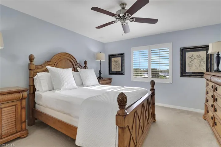 Bedroom with light colored carpet and a ceiling fan