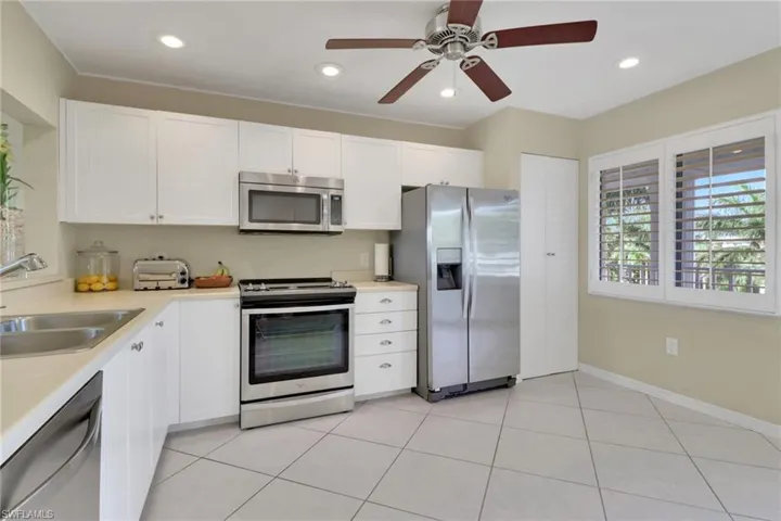 Kitchen featuring white cabinetry, stainless steel appliances, light countertops, light tile patterned floors, and recessed lighting