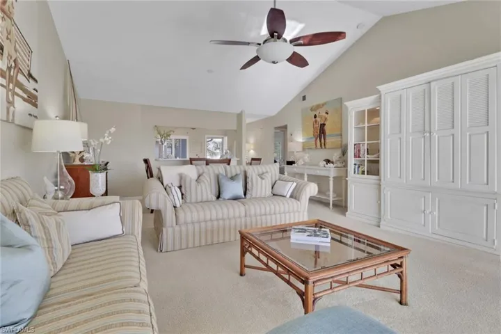 Carpeted living room featuring high vaulted ceiling and a ceiling fan