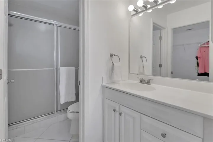 Full bathroom with light tile patterned flooring, vanity, a stall shower, and a walk in closet