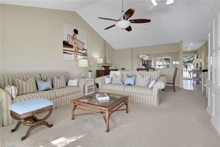 Carpeted living room with ceiling fan and high vaulted ceiling