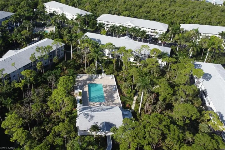 Drone / aerial view of a pool area and apartment complex / building