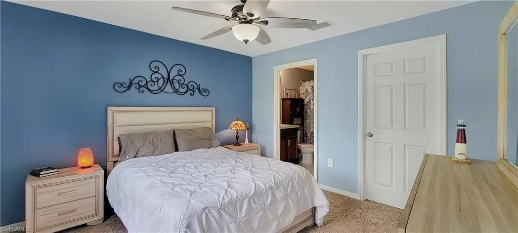 Carpeted bedroom with ensuite bathroom and ceiling fan