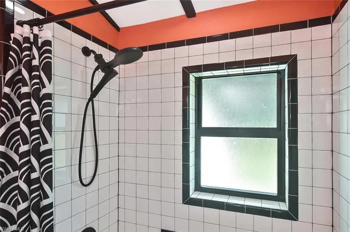 The shower curtain is a perfect accent to the uniquely-patterned black & white tiled flooring with a distinctly Art Deco feel.