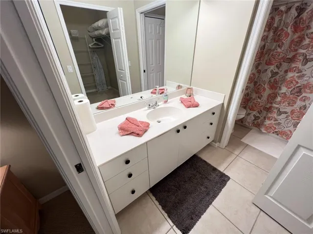 Guest bathroom featuring light tile patterned floors, vanity, and a shower with curtain