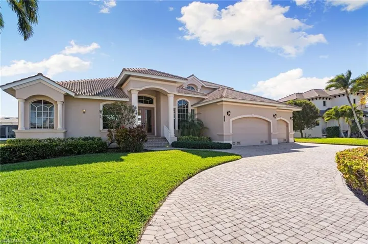 Mediterranean / spanish home with a front lawn, stucco siding, decorative driveway, an attached garage, and a tiled roof