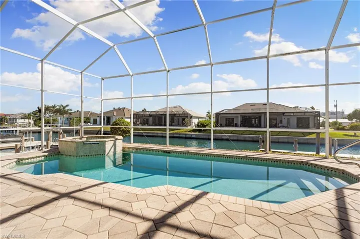 Integrated pool / spa with a residential view, glass enclosure, a sunroom, a water view, and a patio area