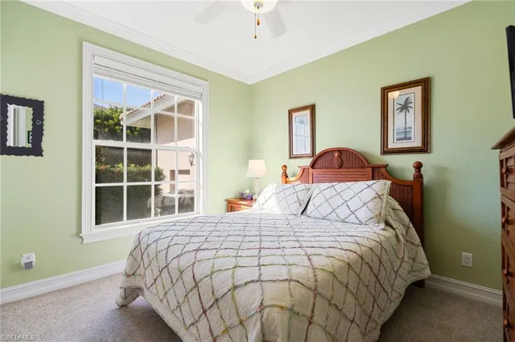 Bedroom featuring ornamental molding, a ceiling fan, and carpet