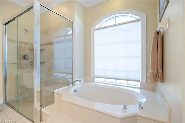 Full bathroom with a bath, a shower stall, and ornamental molding