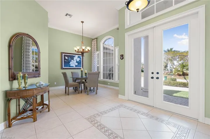 Dining room with light tile patterned flooring, ornamental molding, hanging lights, french doors, and inlaid floor details
