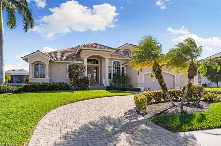 Mediterranean / spanish-style home with french doors, stucco siding, curved driveway, a front lawn, and a tiled roof