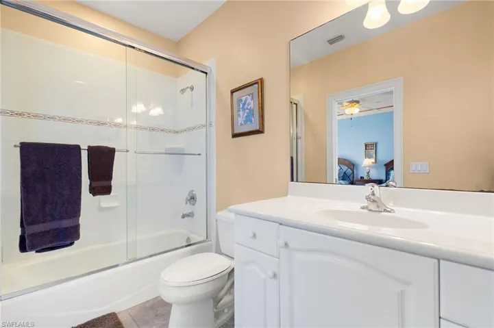 Full bath with connected bathroom, enclosed tub / shower combo, vanity, and light tile patterned floors