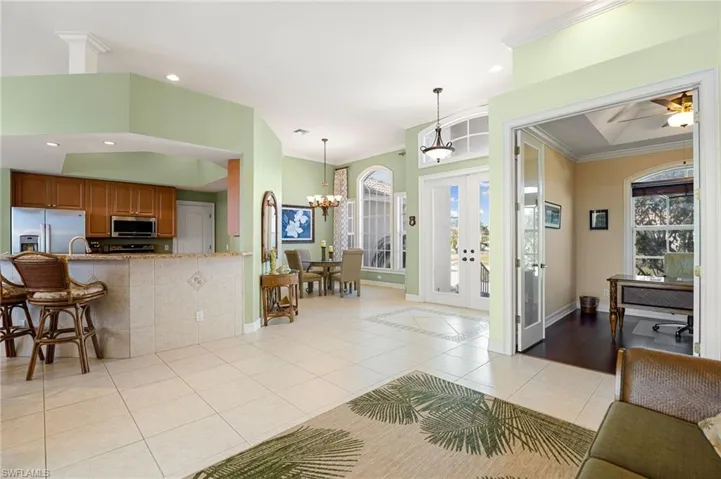 Entryway with light tile patterned floors, french doors, a ceiling fan, crown molding, and a chandelier