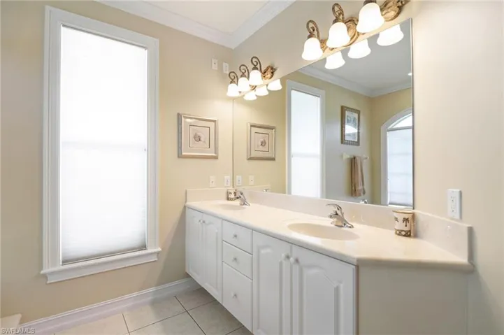 Full bathroom featuring double vanity, ornamental molding, and light tile patterned flooring