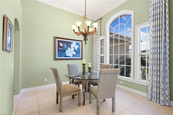 Tiled dining area featuring hanging lights and crown molding