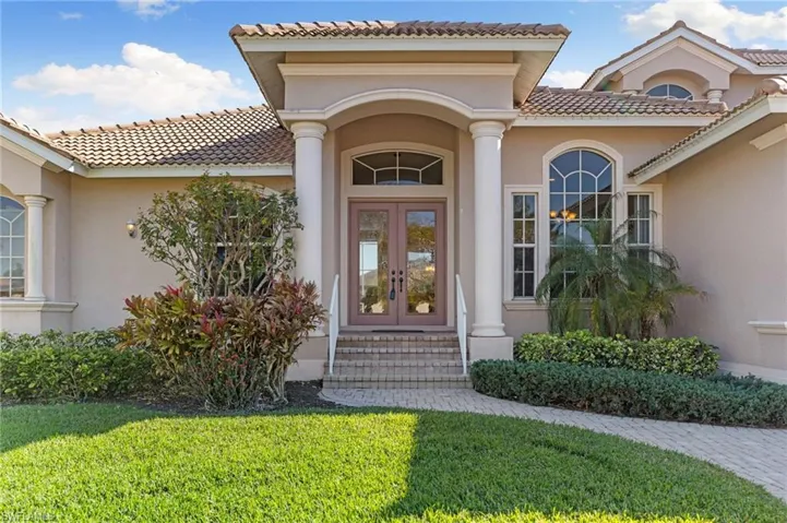 Doorway to property with french doors, stucco siding, a lawn, and a tiled roof