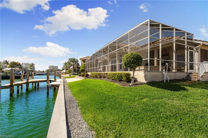Dock area with a sunroom, glass enclosure, a water view, and a yard