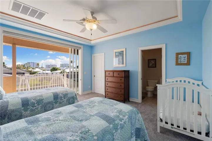 Carpeted bedroom featuring a raised ceiling, access to outside, and ceiling fan