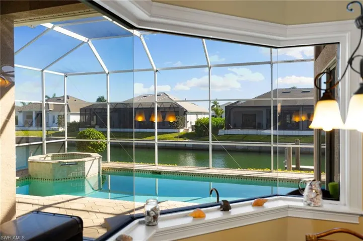 Integrated pool / hot tub featuring a sunroom, a water view, and glass enclosure