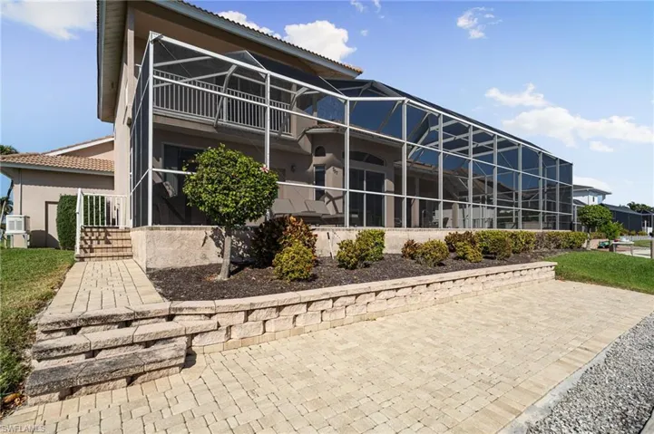 Rear view of house with a sunroom, a lanai, a tiled roof, stucco siding, and a patio area