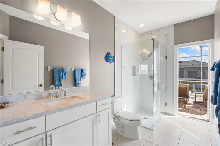 Full bathroom featuring a marble finish shower, vanity, light tile patterned floors, and recessed lighting