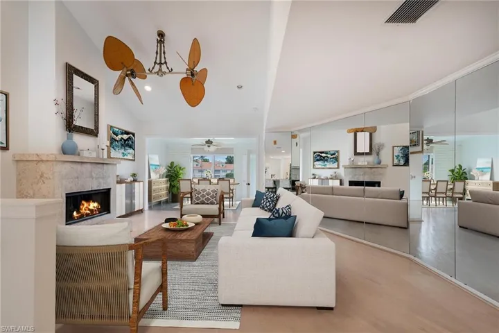 Living room with a fireplace, plenty of natural light, and vaulted ceiling
