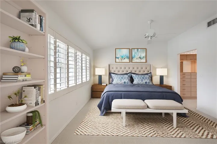 Bedroom with lofted ceiling, a spacious closet, ceiling fan, and light colored carpet