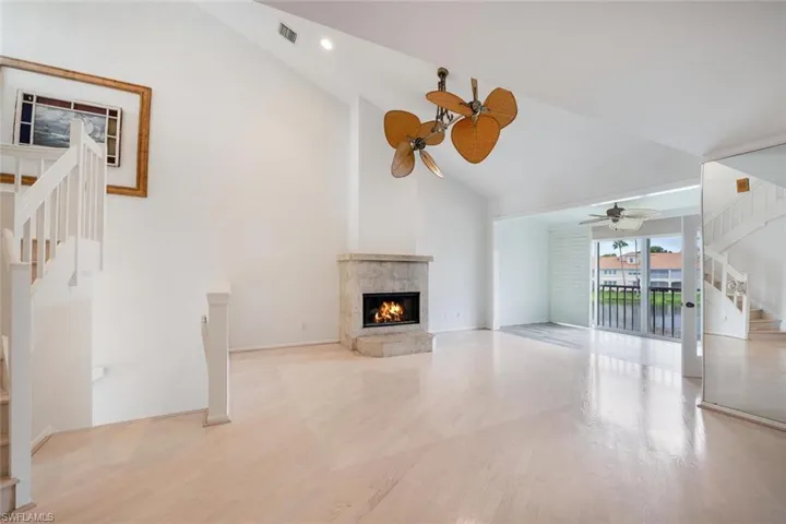 Unfurnished living room with light hardwood / wood-style flooring, lofted ceiling, a premium fireplace, and ceiling fan