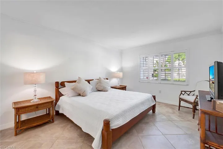 Bedroom with crown molding and light tile patterned flooring