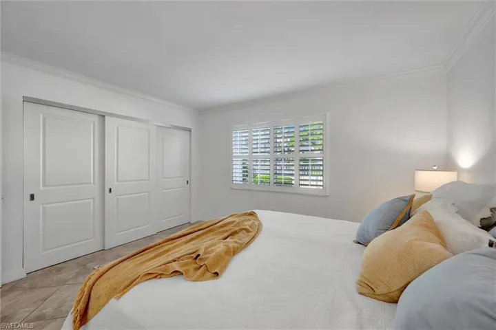 Bedroom with crown molding, a closet, and tile patterned flooring