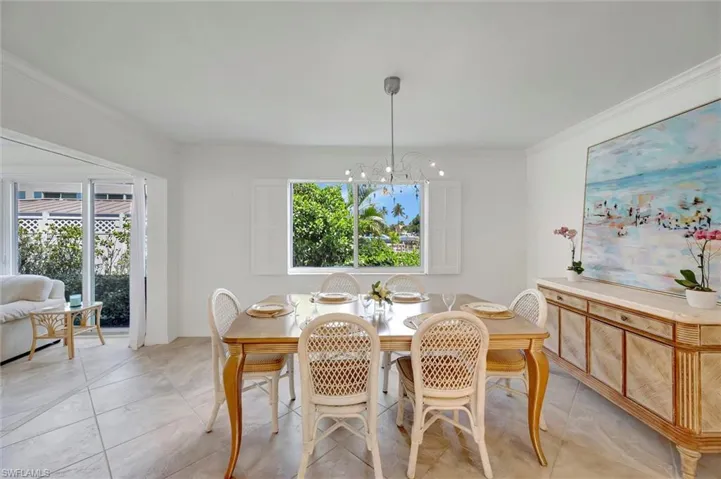 Dining space with crown molding, a chandelier, and light tile patterned floors