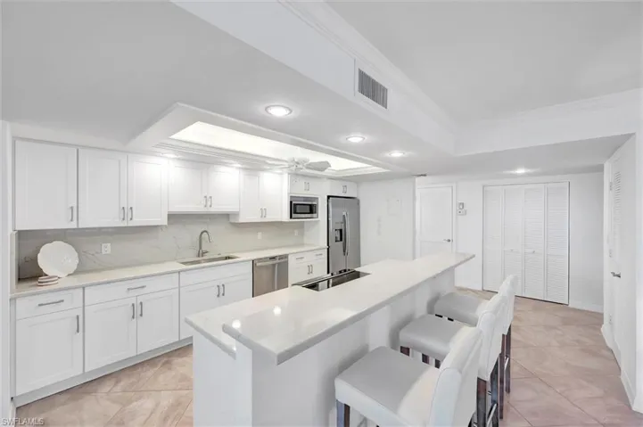 Kitchen with white cabinets, tasteful backsplash, stainless steel appliances, an island with sink, and recessed lighting
